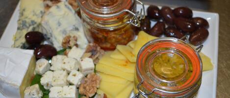 A cheese platter with various cheeses, nuts, and olives on a white plate.