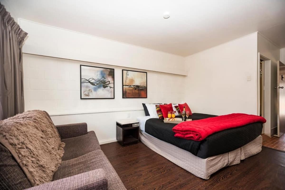 Un dormitorio moderno con una cama grande, un sofá y dos obras de arte colgadas en la pared.