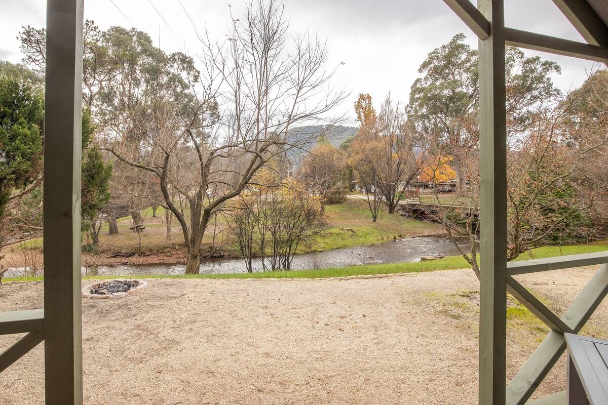 A view from a covered area overlooking a natural landscape with a river, trees, and a distant building.