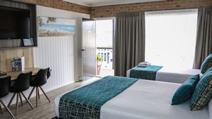 Une chambre d’hôtel avec un lit, un bureau et des chaises, une télévision et une vue sur l’extérieur.
