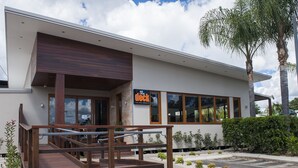 Un bâtiment moderne doté d’une terrasse en bois et d’une enseigne indiquant : « The Deck Club Hotel-Chinchilla ».