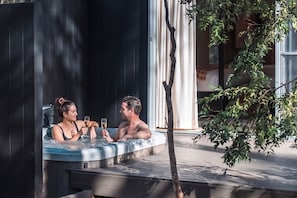 A couple in a hot tub with a tree and a building in the background. - Clayfields Hunter Valley (Pokolbin)