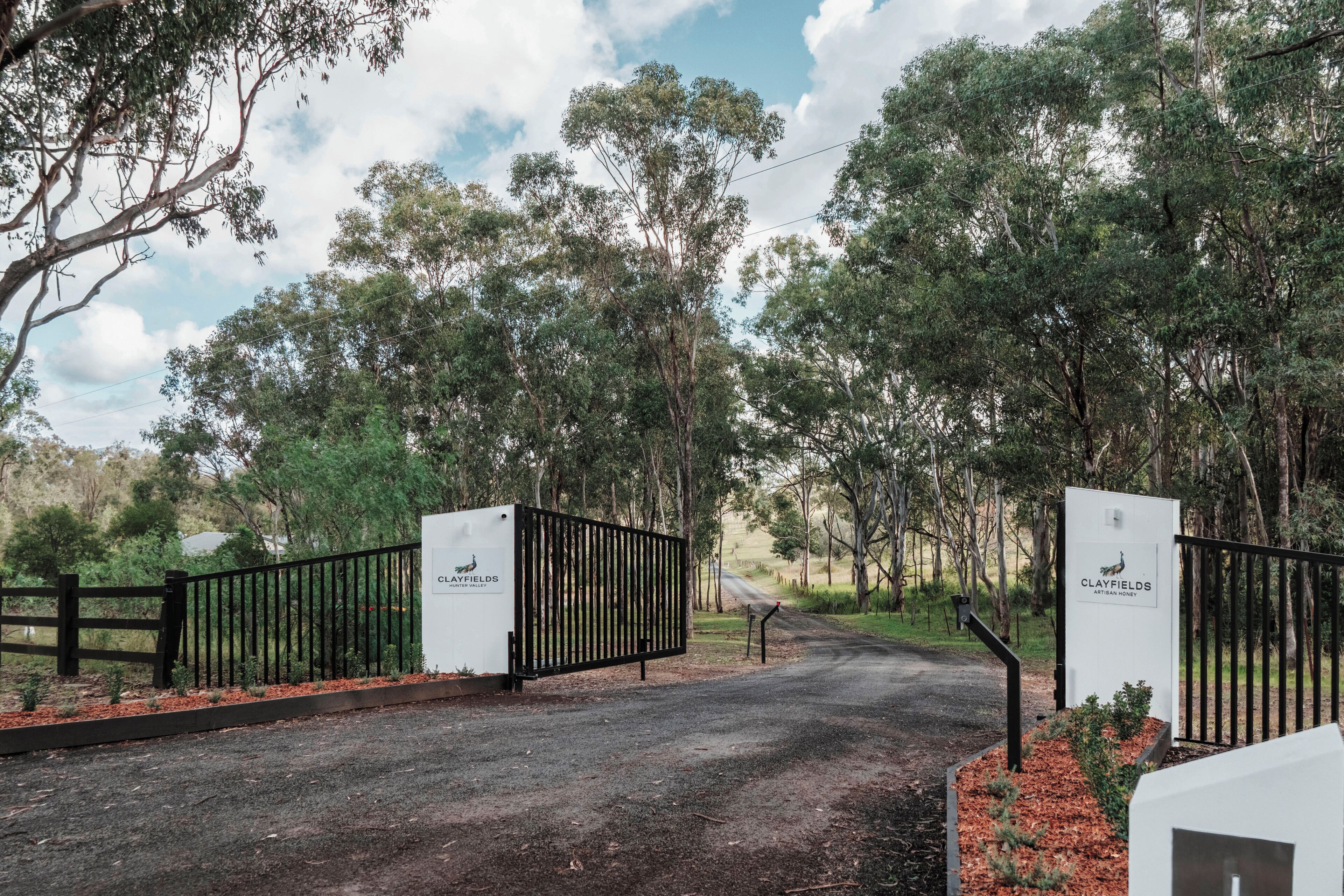 A gated entrance to a property with a sign indicating 'Clayfields Hunter Valley Artisan Honey.'