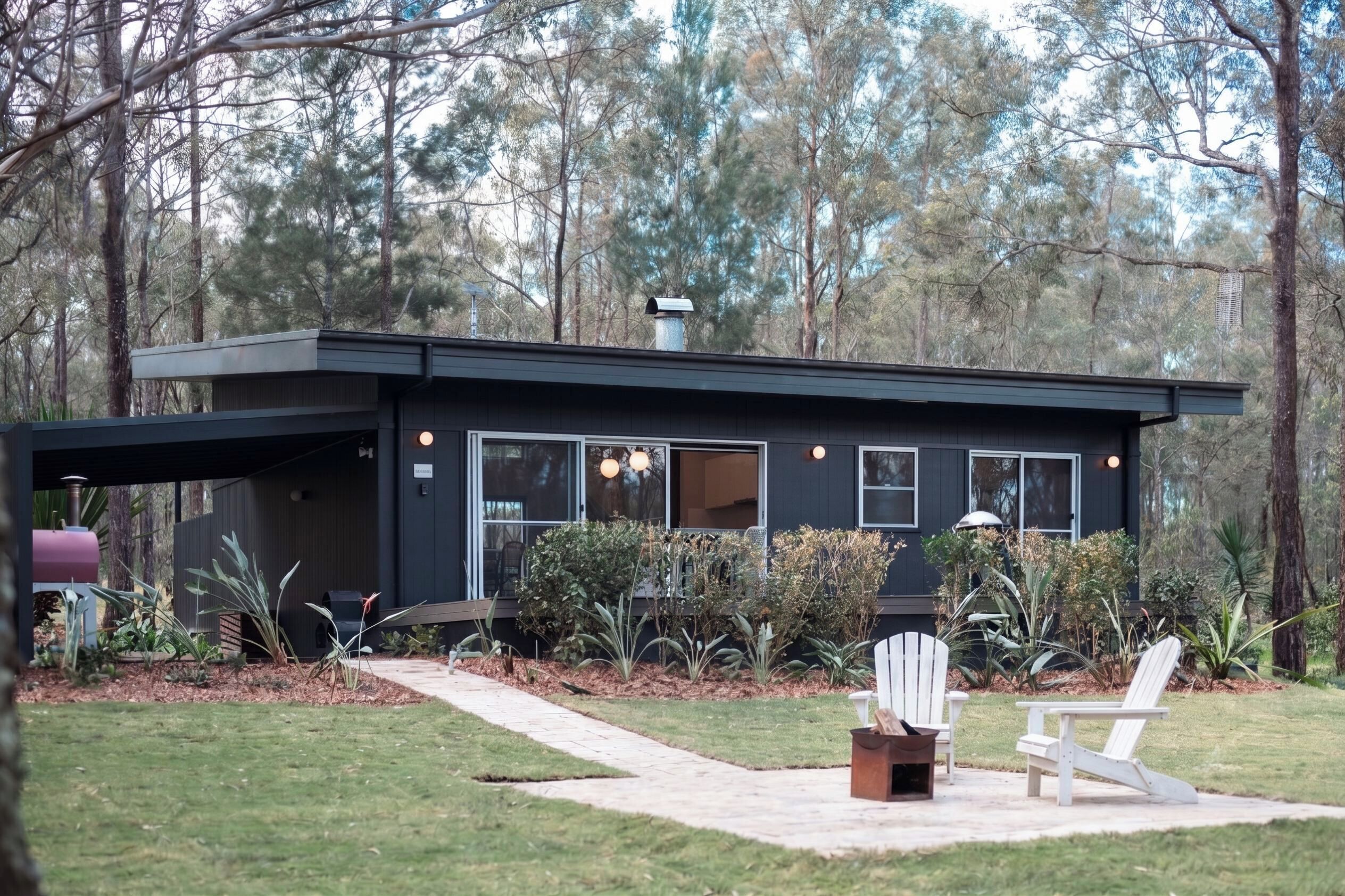 A modern house with a covered porch, a barbecue grill, and a seating area with chairs.