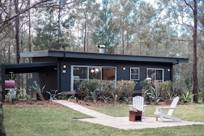 A modern house with a covered porch, a barbecue grill, and a seating area with chairs.