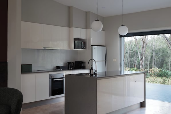A modern kitchen with a central island, built-in appliances, and a view of the outdoors.