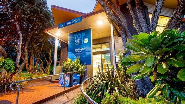 A reception area with a sign for 'TOP 10 Holiday Parks Classic Wellington' and a building entrance. - Wellington TOP 10 Holiday Park (Lower Hutt)
