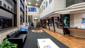 A spacious lobby with a black leather sofa, a reception desk, a large flat-screen TV, and a wooden floor. - Wellington TOP 10 Holiday Park (Lower Hutt)