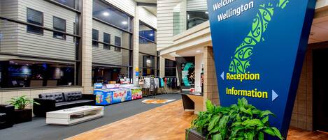 A modern reception area with a large sign indicating directions to the reception and information.