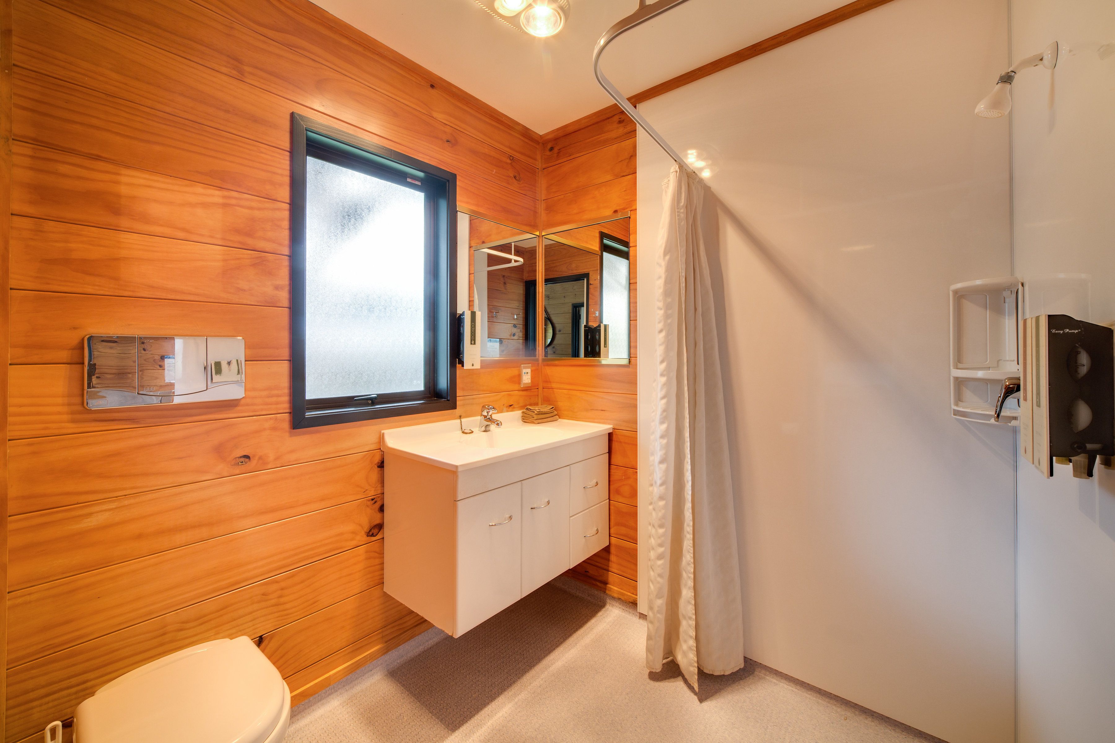 A modern bathroom with wooden paneling, a white sink, and a large mirror.