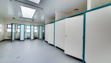 Un baño moderno y limpio, con varios cubículos, tragaluces y piso sencillo.