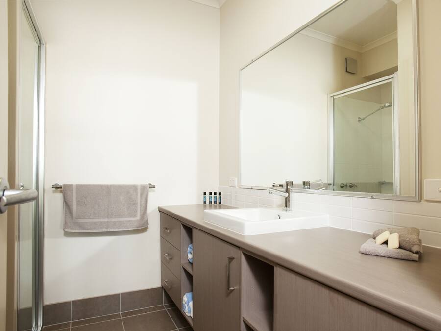 A bathroom with a shower, a sink, a mirror, and a towel rack.