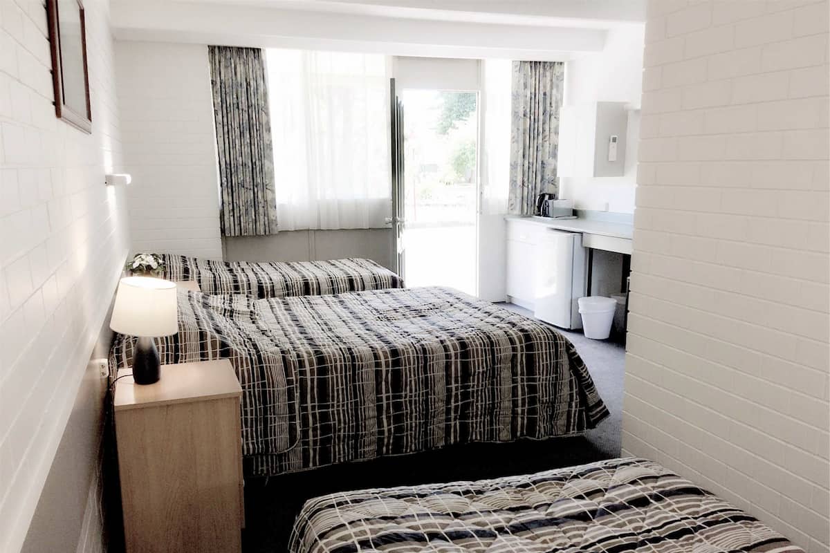 A hotel room with two beds, a nightstand, a desk, and a window with curtains.