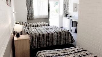 A hotel room with two beds, a nightstand, a desk, and a window with curtains.