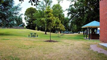 A grassy park area with a picnic table and a gazebo.