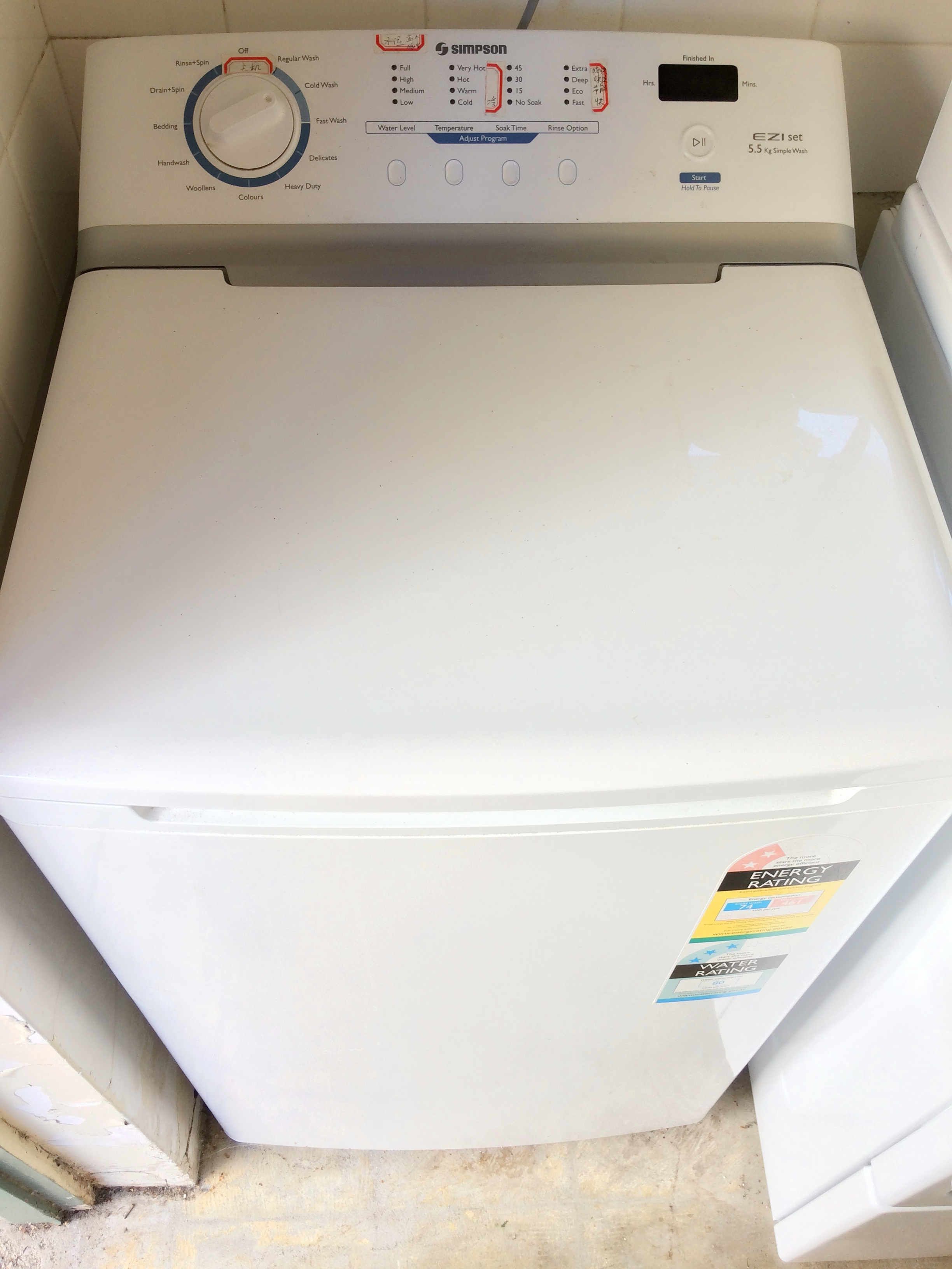 A front view of a white washing machine with control panel, energy rating label, and water rating label.