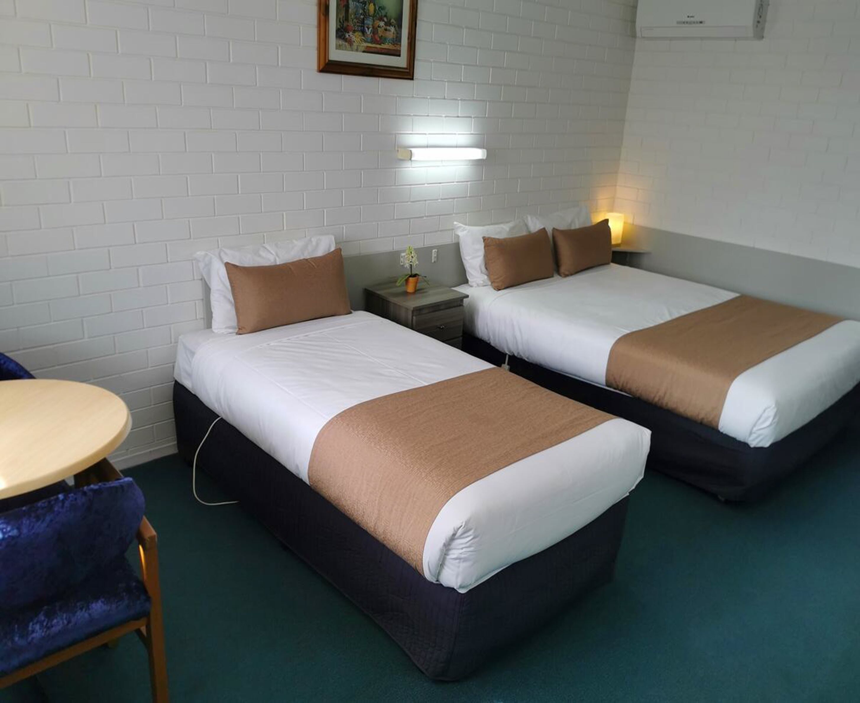 A hotel room with two beds, a small table, and a chair.