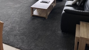 A modern living room with a large flat-screen TV, two black leather sofas, a wooden coffee table, and a view of a residential area through large windows. - Sails Luxury Apartments, Forster (Forster)