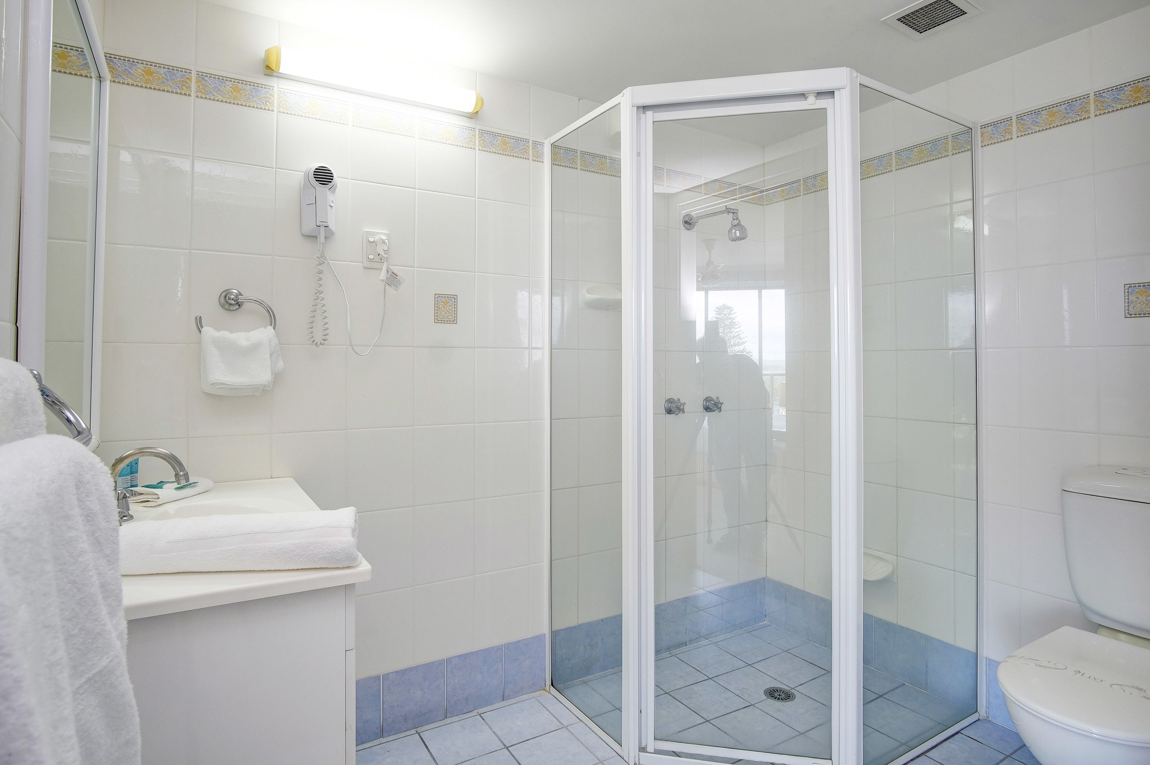Een badkamer met een douche met glazen wand, een wastafel met handdoek en een toilet.