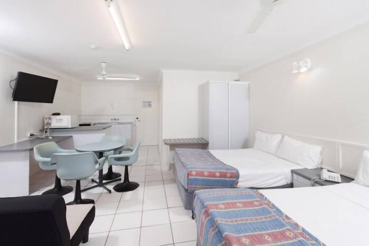 A hotel room with a bed, bedside table, and a desk with a chair.