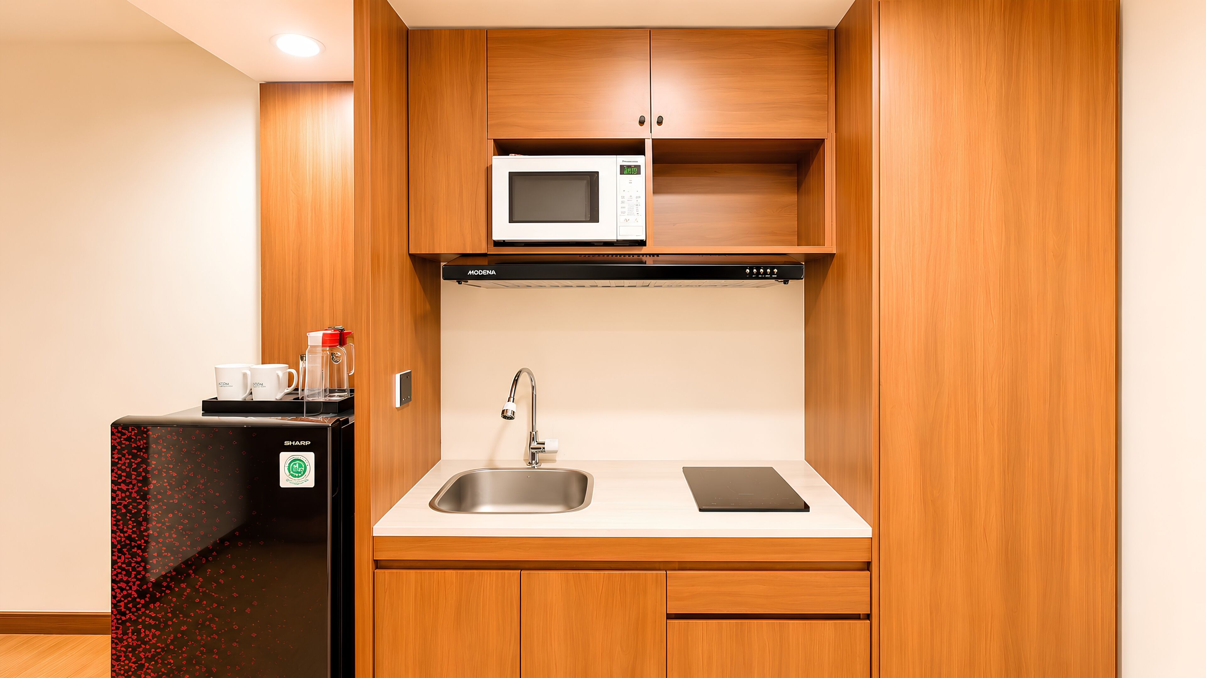 Una cocina compacta equipada con microondas, cafetera y refrigerador.