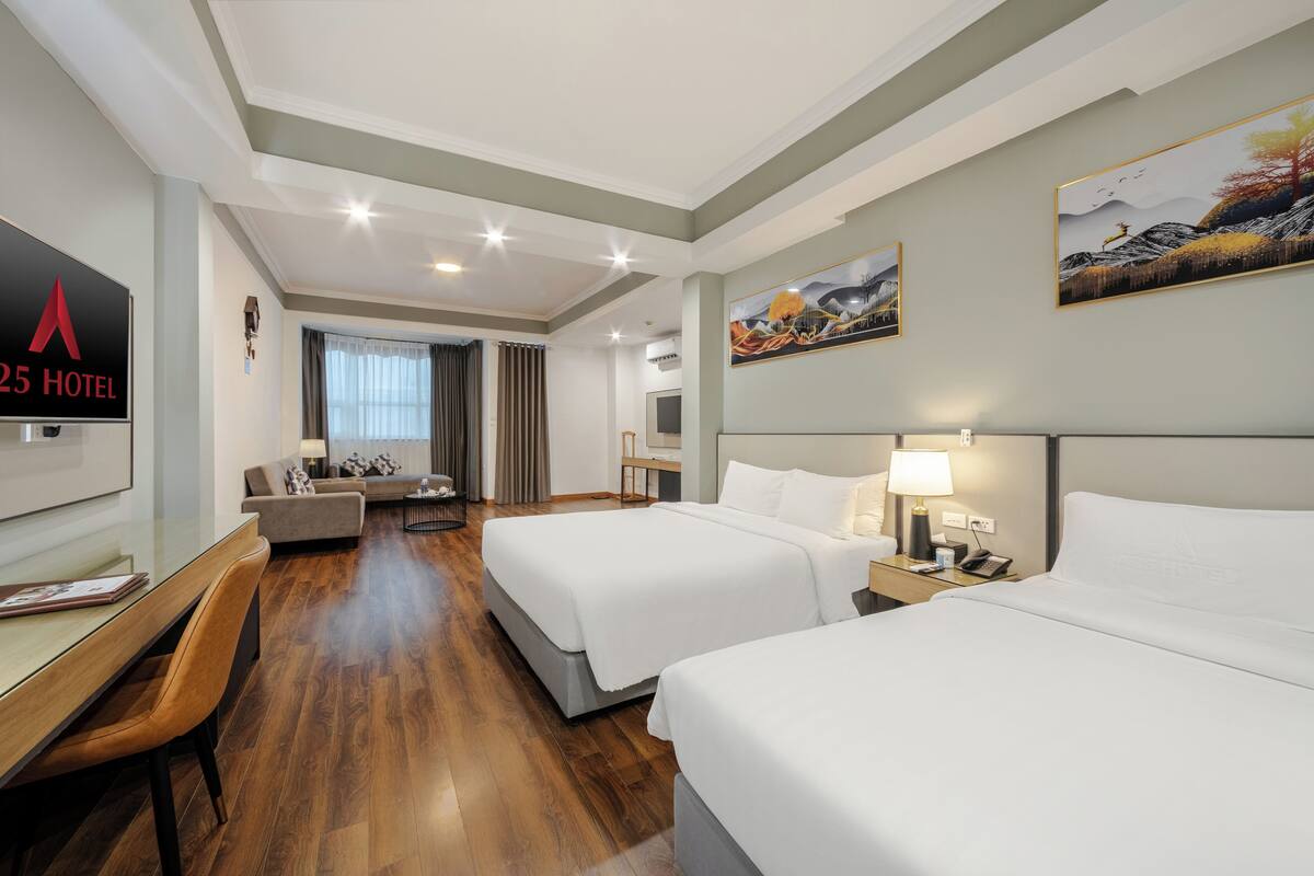 Een hotelkamer met twee bedden, een bureau, een bank en een televisie.