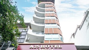 A hotel entrance with a sign for A25 Hotel Camelia, including amenities like rest service, restaurant, and travel tours.