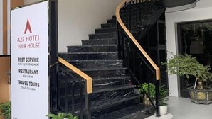 A staircase with black marble steps and wooden handrails, leading to a hotel entrance.