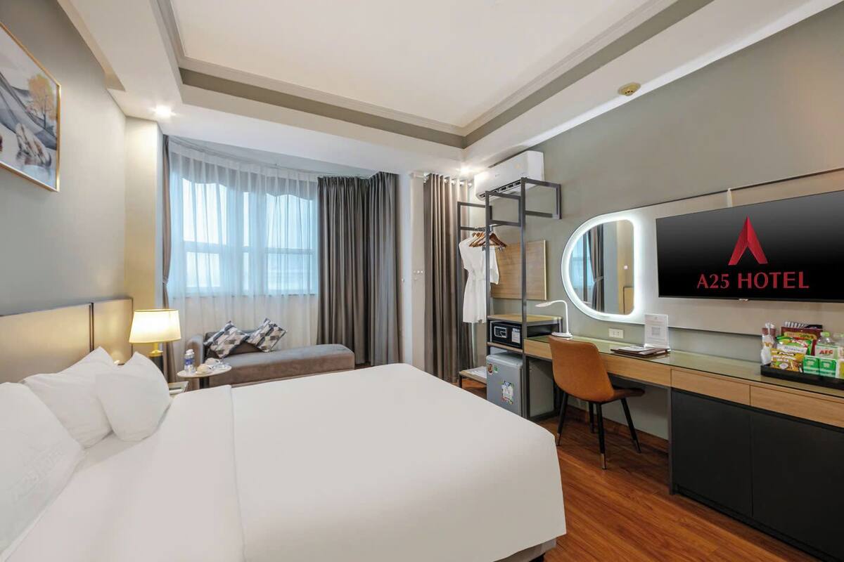 Een hotelkamer met een bed, een bureau, een stoel, een televisie en een minibars.