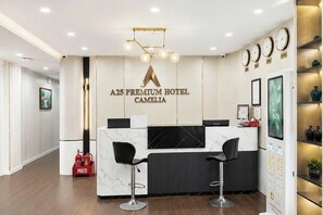 Un mostrador de recepción con un logotipo, dos taburetes de bar, un extintor y una pantalla digital.