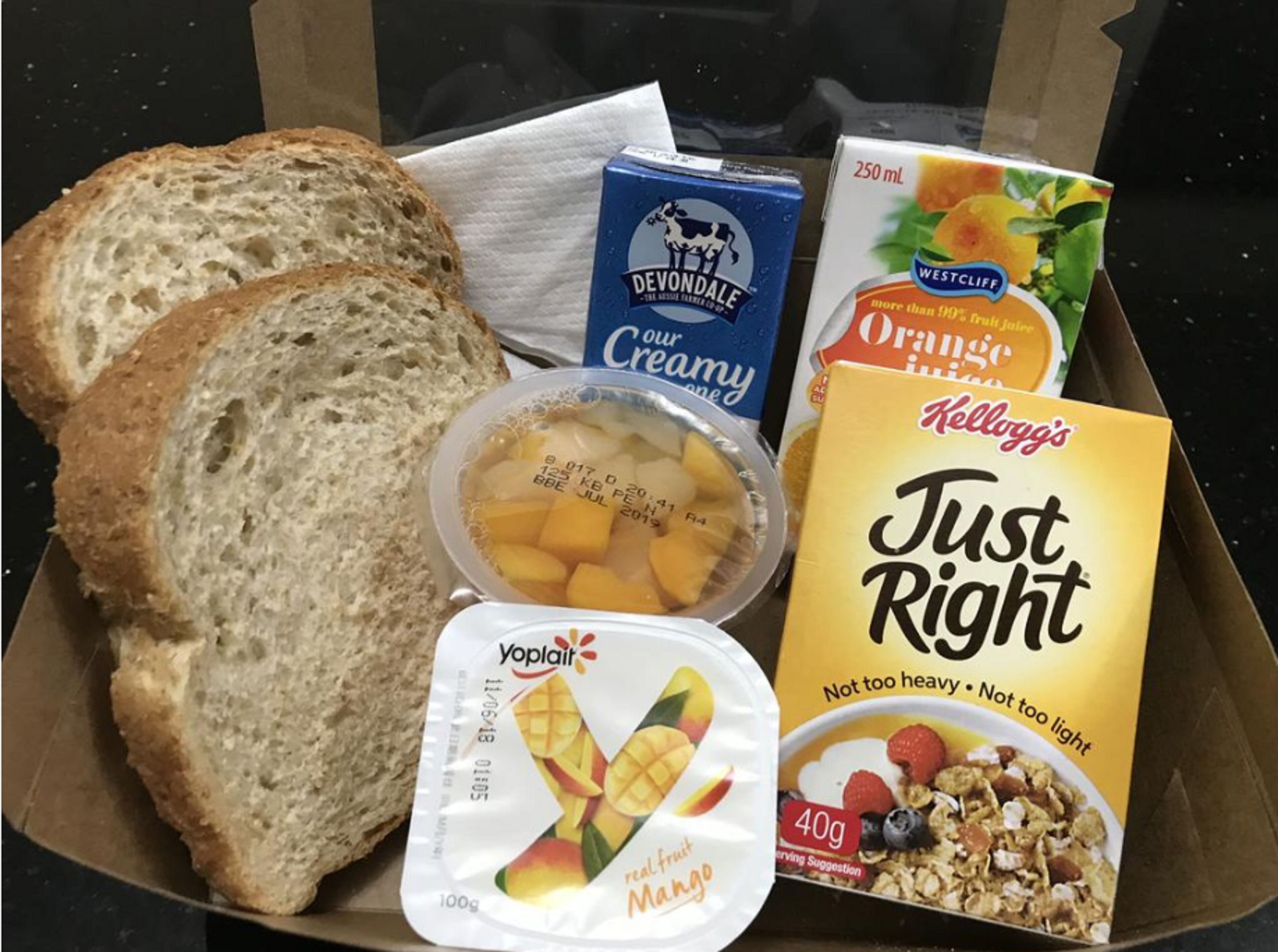 Una caja con cereales Just Right, queso crema Devondale, yogur Yoplait, jugo de naranja Westcliff y rebanadas de pan.