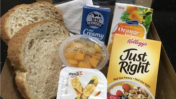 Una caja con cereales Just Right, queso crema Devondale, yogur Yoplait, jugo de naranja Westcliff y rebanadas de pan.