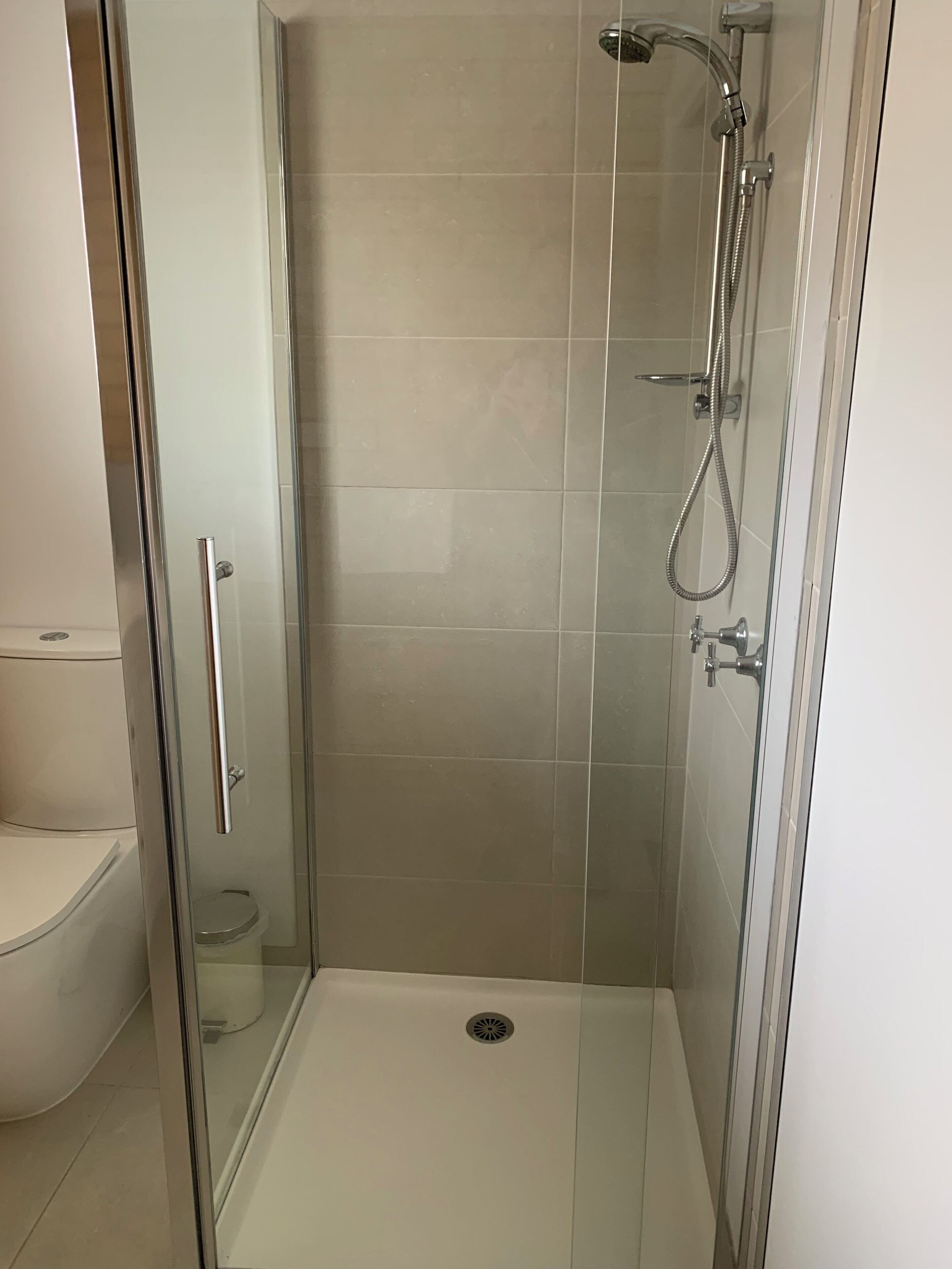 A glass-enclosed shower stall with a toilet and sink in a bathroom.