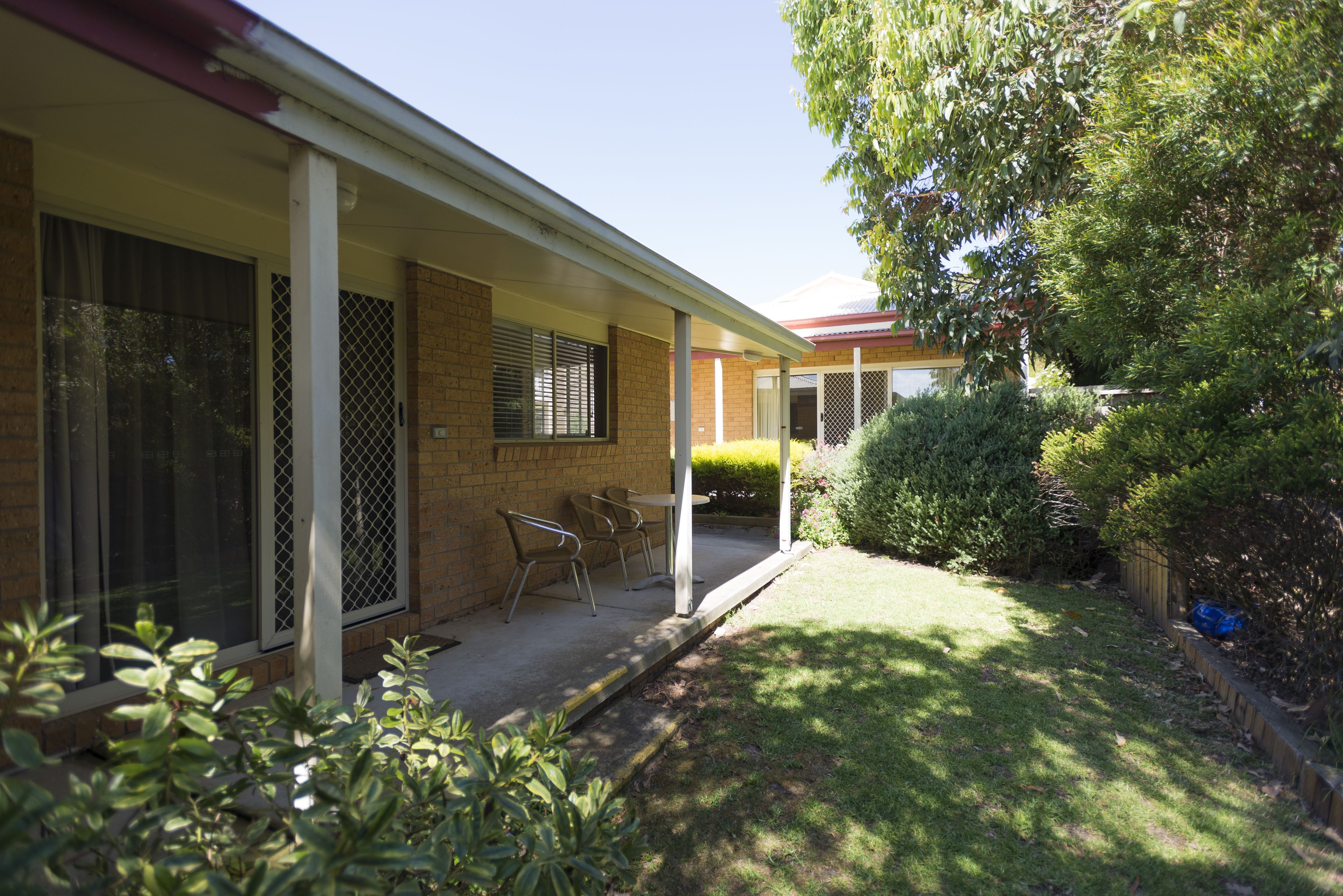 A house with a covered porch, a brick exterior, and a small lawn.