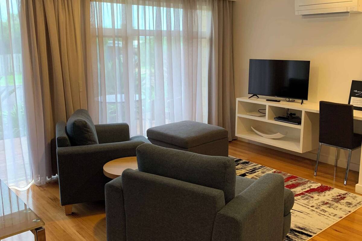 A modern living room with grey sofas, a flat-screen TV, and a white entertainment unit.