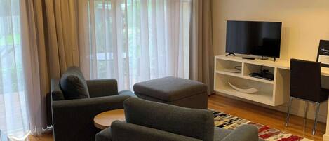 A modern living room with grey sofas, a flat-screen TV, and a white entertainment unit.