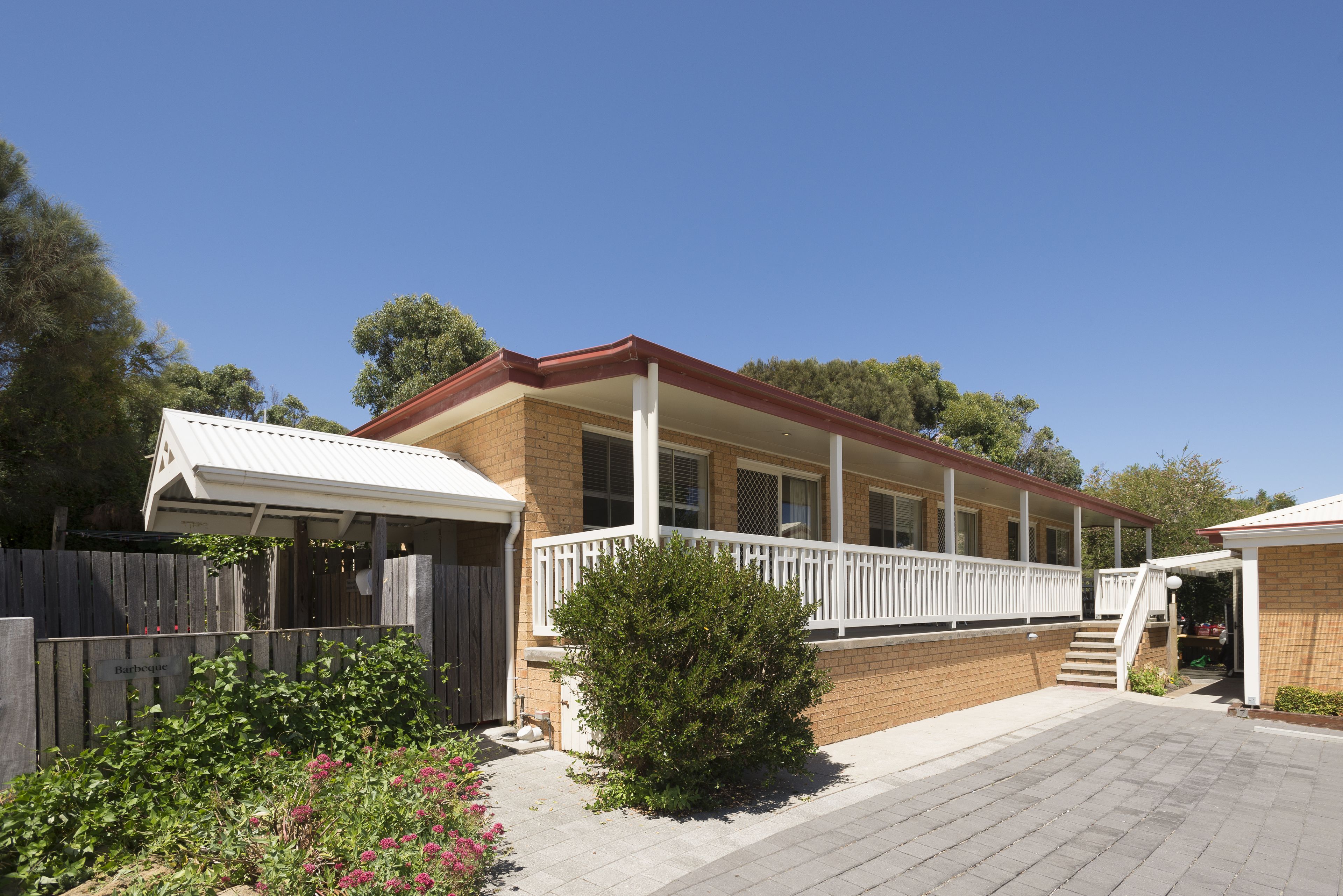 A two-story house with a covered porch, a brick exterior, and a wooden fence.