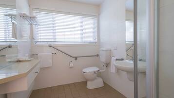 A bathroom with a toilet, sink, and window with blinds.
