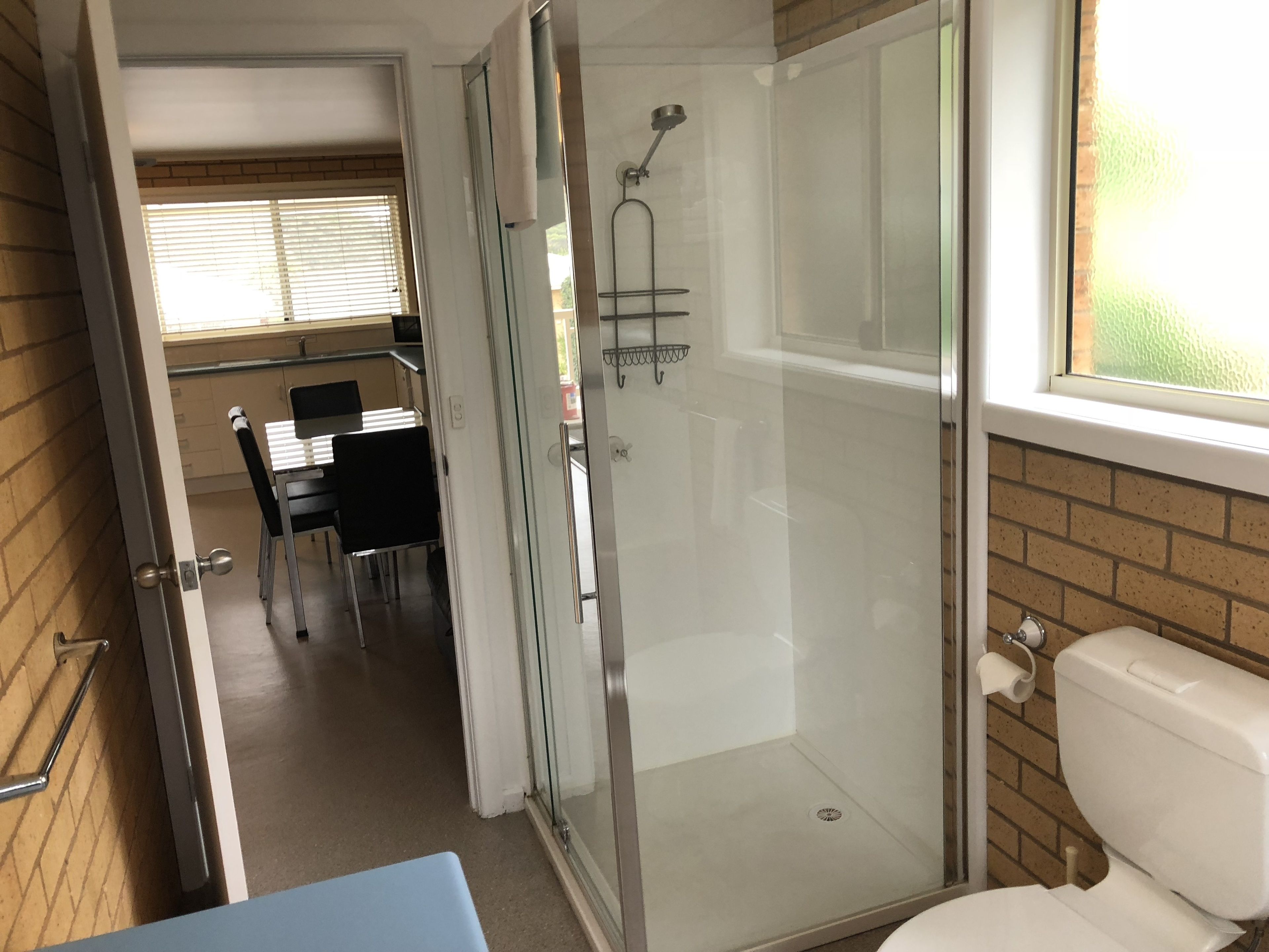 Een badkamer met een douchecabine, een toilet en een wastafel.