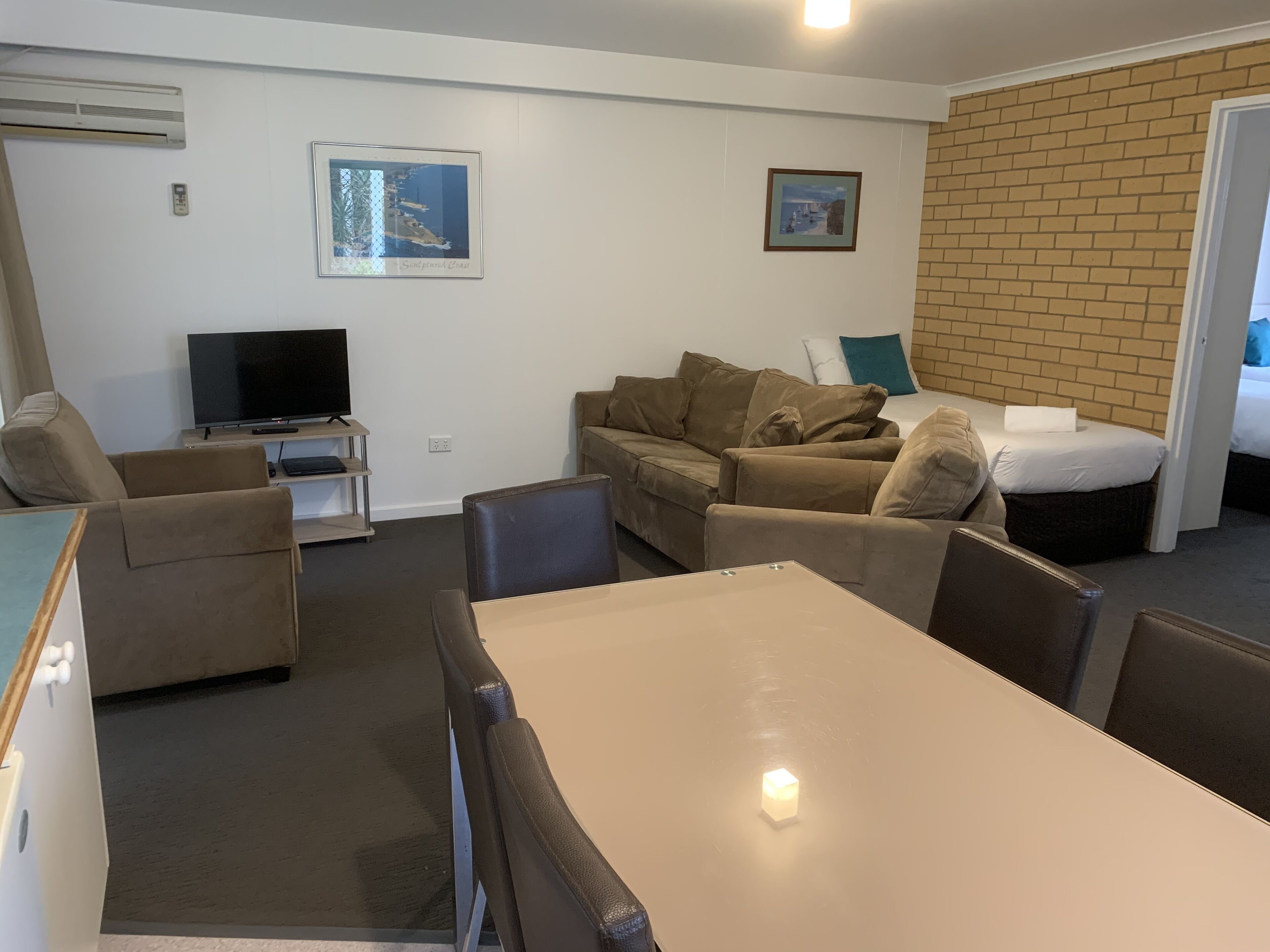 A compact living space with a sofa set, a TV, a small table, and a bed.