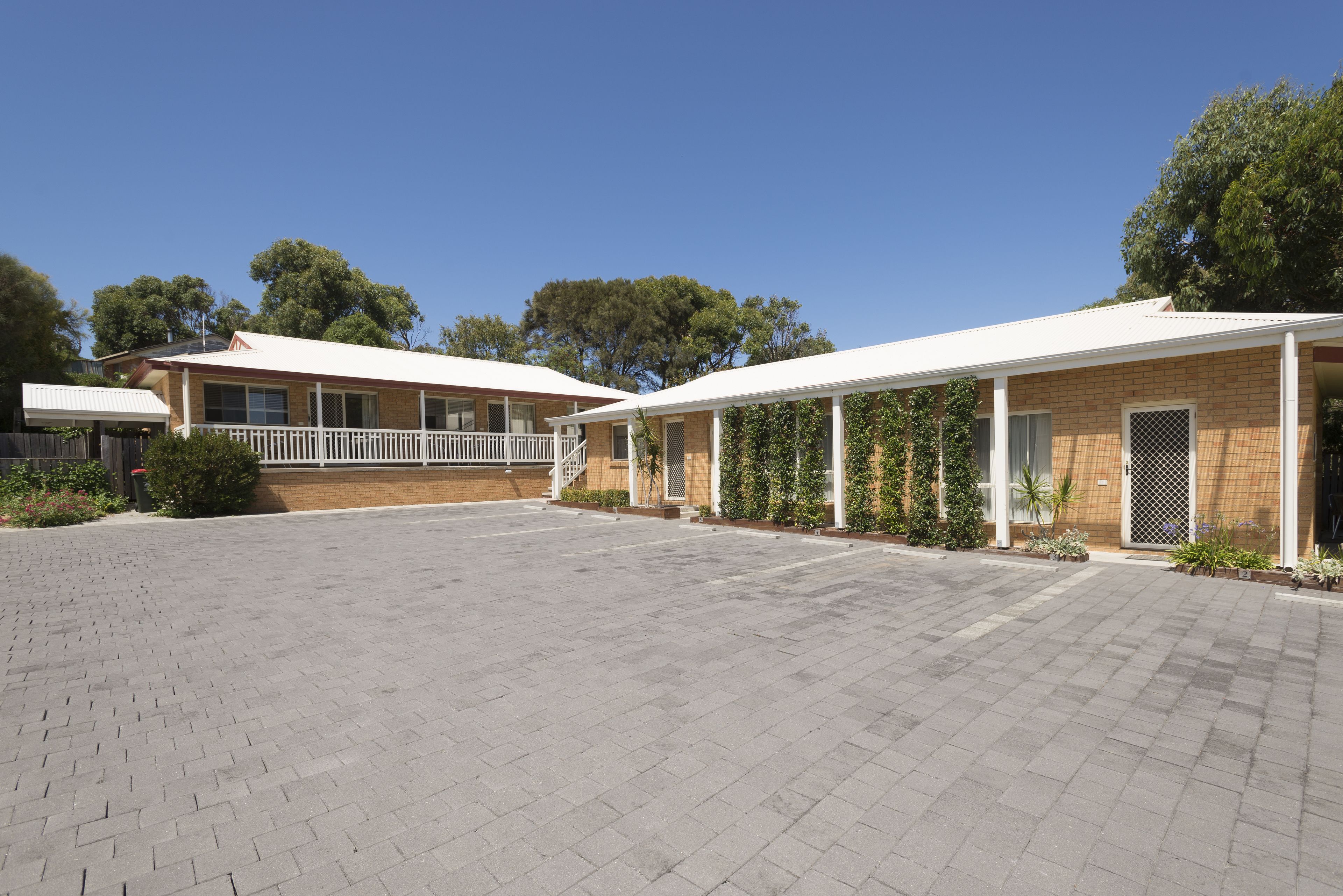 A building with a covered outdoor area, a brick facade, and a clear sky.