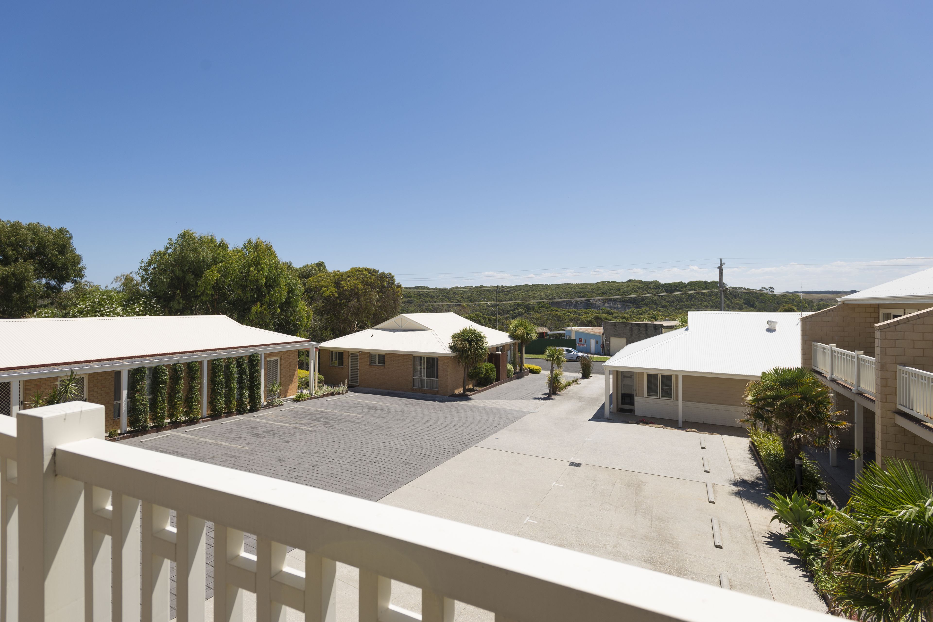 A hotel courtyard with a paved area, several buildings with flat roofs, and a clear blue sky.