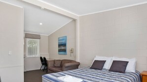 Ein Schlafzimmer mit einem Bett, einem Sessel, einem Gemälde und einem Telefon an der Wand.