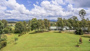 A grassy field with trees and a building in the background. - Vineyard Hill (Lovedale)