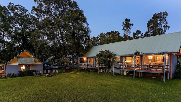 A campground with multiple cabins, a grassy area, and trees in the background. - Vineyard Hill (Lovedale)