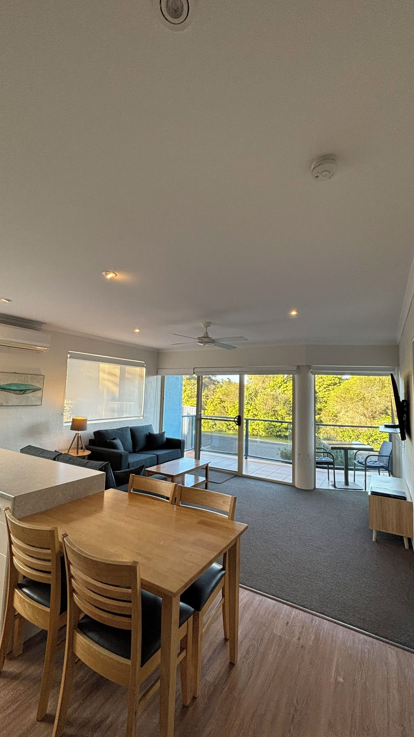 A modern interior with a dining area, a sofa, and a view of the outdoors.
