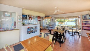 Ein Restaurant mit Seeblick, ausgestattet mit einem Holztisch und -stühlen, einem Deckenventilator und verschiedenen gerahmten Bildern an den Wänden.