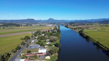 An aerial view of a riverside town with a main road, residential areas, and fields.