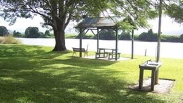 A gazebo with a table and chairs in a grassy area near a body of water.