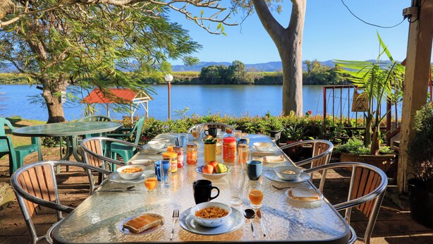 Ein Tisch ist für das Frühstück gedeckt, mit Blick auf einen See und Berge.